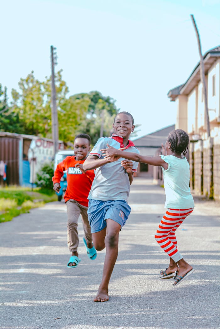 Happy children running and playing on a sunny day in a lively neighborhood street.