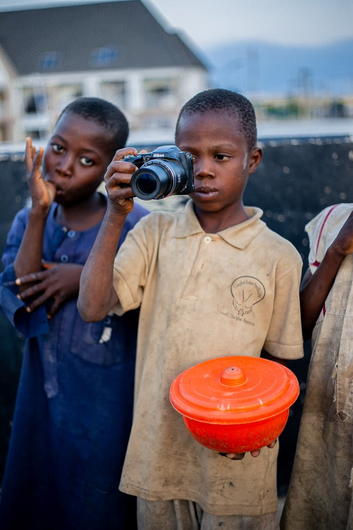 Two boys playfully engaging with a camera outdoors, showcasing creativity and curiosity.